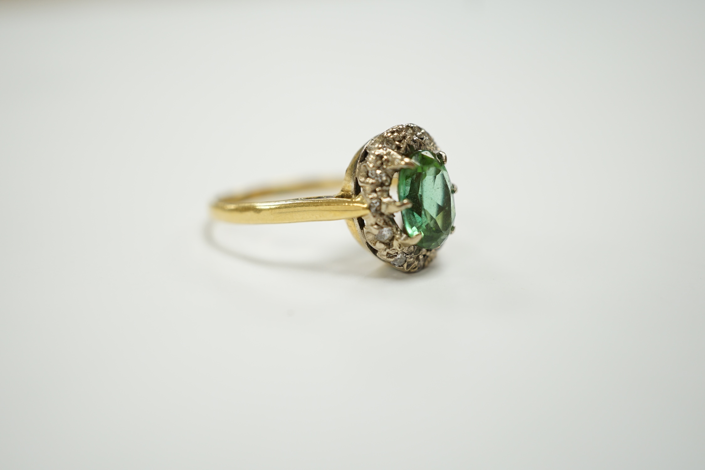 A modern 18ct gold, green tourmaline and diamond set oval cluster ring, size O/P, gross weight 3.5 grams.